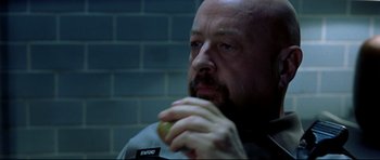 Movie still from “Freddy vs. Jason” (2003), directed by Ronny Yu – A man with a shaved head eating an apple; Close Up shot, High angle