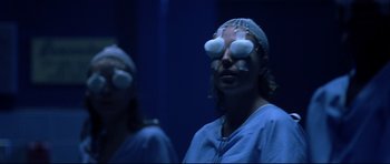 Movie still from “Freddy vs. Jason” (2003), directed by Ronny Yu – A woman in a surgical gown and head band with two other women; Close Up shot, Over the shoulder angle
