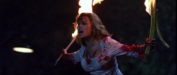 Movie still from “Freddy vs. Jason” (2003), directed by Ronny Yu – A woman holding a stick with a fire in it's mouth; Medium shot, Over the shoulder angle