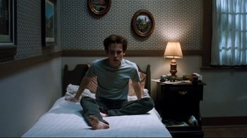Movie still from “Freddy's Dead: The Final Nightmare” (1991), directed by Rachel Talalay – A man sitting on top of a bed in a bedroom; Medium shot, High angle