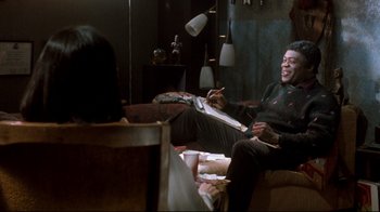 Movie still from “Freddy's Dead: The Final Nightmare” (1991), directed by Rachel Talalay – A man sitting on a couch while holding a pencil; Medium shot, Over the shoulder angle