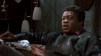 Movie still from “Freddy's Dead: The Final Nightmare” (1991), directed by Rachel Talalay – A man sitting on top of a couch in front of a lamp; Medium shot, High angle