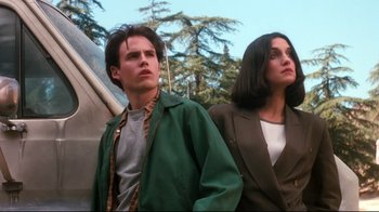 Movie still from “Freddy's Dead: The Final Nightmare” (1991), directed by Rachel Talalay – A man and a woman standing next to each other in front of trees; Medium shot, Low angle
