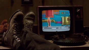 Movie still from “Freddy's Dead: The Final Nightmare” (1991), directed by Rachel Talalay – A person sitting in front of a tv with their feet on the ground; Wide shot, Over the shoulder angle