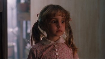 A little girl with pigtails is standing in a room