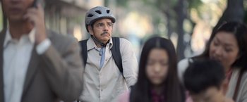 Movie still from “The Valet” (2022), directed by Richard Wong – A man wearing a bicycle helmet while standing next to a woman; Close Up shot, Over the shoulder angle