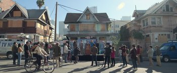 Movie still from “The Valet” (2022), directed by Richard Wong – A group of people standing in front of an old house; Extreme Wide shot, Low angle