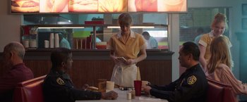 Movie still from “The Valet” (2022), directed by Richard Wong – A woman standing in front of a group of people at a table; Medium shot, Over the shoulder angle