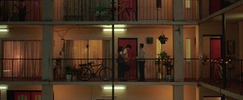 Movie still from “The Valet” (2022), directed by Richard Wong – A couple of people standing on a balcony next to each other; Extreme Wide shot, Overhead angle