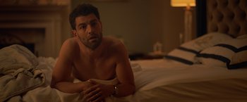 Movie still from “The Valet” (2022), directed by Richard Wong – A man laying on a bed in a hotel room; Medium shot, Over the shoulder angle