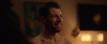 Movie still from “The Valet” (2022), directed by Richard Wong – A man with a beard is smiling for the camera; Close Up shot, Over the shoulder angle