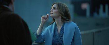 Movie still from “The Valet” (2022), directed by Richard Wong – A woman in a blue jacket is sitting outside; Medium shot, Over the shoulder angle