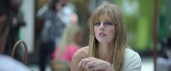 Movie still from “The Valet” (2022), directed by Richard Wong – A beautiful woman sitting in front of a group of people; Close Up shot, Low angle