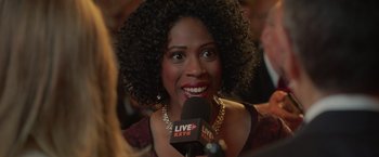 Movie still from “The Valet” (2022), directed by Richard Wong – A woman with curly hair is talking into a microphone; Close Up shot, Over the shoulder angle