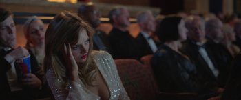 Movie still from “The Valet” (2022), directed by Richard Wong – A woman sitting in front of other people in an audience; Medium shot, Low angle
