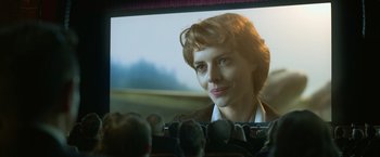 Movie still from “The Valet” (2022), directed by Richard Wong – A woman sitting in front of a large screen television; Close Up shot, Over the shoulder angle