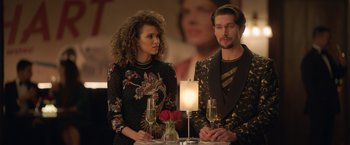 Movie still from “The Valet” (2022), directed by Richard Wong – A man and a woman sitting at a table with champagne; Medium shot, Over the shoulder angle