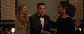 Movie still from “The Valet” (2022), directed by Richard Wong – A man in a tuxedo holding a red box in front of two other people; Medium shot, Low angle
