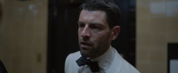 Movie still from “The Valet” (2022), directed by Richard Wong – A person wearing a suit and tie; Close Up shot, Low angle
