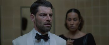 Movie still from “The Valet” (2022), directed by Richard Wong – A man wearing a suit and a bow tie next to a woman in a black dress; Close Up shot, Over the shoulder angle