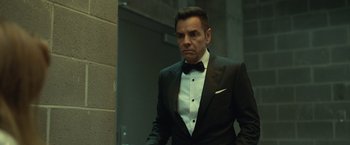 Movie still from “The Valet” (2022), directed by Richard Wong – A man in a tuxedo standing in front of a wall; Medium shot, Low angle
