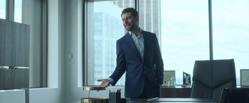 Movie still from “The Valet” (2022), directed by Richard Wong – A man wearing a suit and tie standing in front of a window; Medium shot, Over the shoulder angle