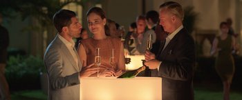 Movie still from “The Valet” (2022), directed by Richard Wong – A group of people standing around a table with wine glasses; Medium shot, Over the shoulder angle