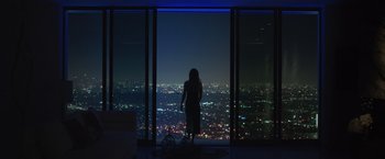 Movie still from “The Valet” (2022), directed by Richard Wong – A woman standing in front of a large window at night; Wide shot, High angle