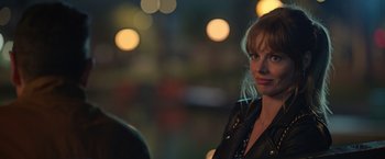 Movie still from “The Valet” (2022), directed by Richard Wong – A woman wearing a leather jacket standing in front of lights; Close Up shot, Over the shoulder angle
