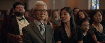 Movie still from “The Valet” (2022), directed by Richard Wong – An older man and a younger woman in front of an audience; Close Up shot, Over the shoulder angle