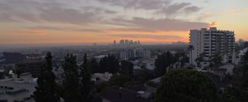 Movie still from “The Valet” (2022), directed by Richard Wong – A view of a city at sunset from a hill; Extreme Wide shot, High angle