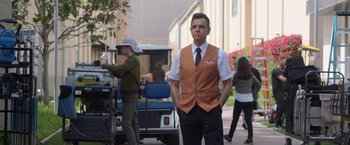 Movie still from “The Valet” (2022), directed by Richard Wong – A man in a vest and tie standing in front of a golf cart; Medium shot, Over the shoulder angle