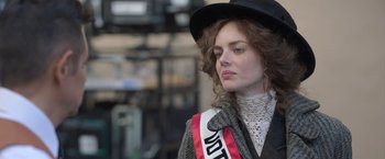 Movie still from “The Valet” (2022), directed by Richard Wong – A woman wearing a black hat and holding a red ribbon; Close Up shot, Low angle