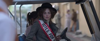 Movie still from “The Valet” (2022), directed by Richard Wong – A woman in a black hat holding a tablet in her hand; Close Up shot, Low angle