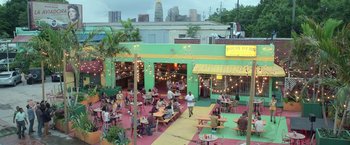 Movie still from “The Valet” (2022), directed by Richard Wong – People are sitting at tables in an outdoor restaurant; Extreme Wide shot, High angle