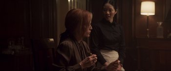 Movie still from “French Exit” (2020), directed by Azazel Jacobs – Two women are sitting in a room and one of them is holding her hands up; Medium shot, Over the shoulder angle