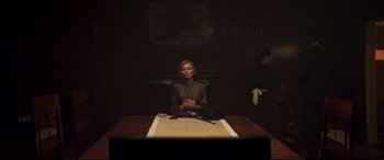 Movie still from “French Exit” (2020), directed by Azazel Jacobs – A woman sitting at a table in front of a fireplace; Medium shot, Low angle