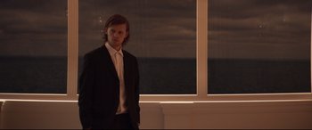 Movie still from “French Exit” (2020), directed by Azazel Jacobs – A man standing in front of a large window; Medium shot, Over the shoulder angle