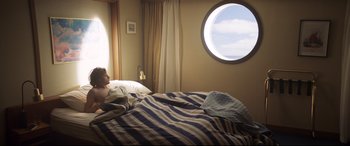 Movie still from “French Exit” (2020), directed by Azazel Jacobs – A person laying in a bed looking out of a window; Wide shot, High angle