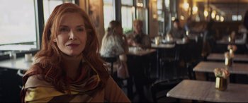 Movie still from “French Exit” (2020), directed by Azazel Jacobs – A woman sitting at a table in front of a group of people; Close Up shot, Over the shoulder angle