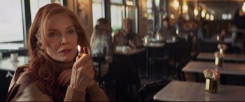 Movie still from “French Exit” (2020), directed by Azazel Jacobs – A woman sitting at a table holding a candle; Close Up shot, Over the shoulder angle