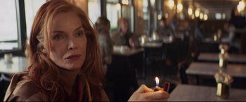 Movie still from “French Exit” (2020), directed by Azazel Jacobs – A woman sitting at a table holding a lit candle; Close Up shot, Over the shoulder angle