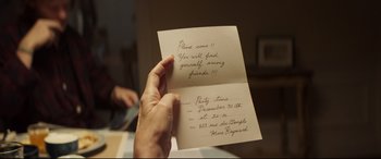 Movie still from “French Exit” (2020), directed by Azazel Jacobs – A person holding up a card that reads , " please come !!"; Extreme Close Up shot, High angle