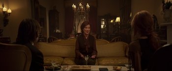 Movie still from “French Exit” (2020), directed by Azazel Jacobs – A woman sitting on top of a couch in a living room; Medium shot, Low angle