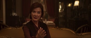 Movie still from “French Exit” (2020), directed by Azazel Jacobs – An older woman claps her hands while sitting at a table; Close Up shot, Over the shoulder angle