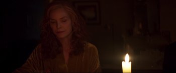 Movie still from “French Exit” (2020), directed by Azazel Jacobs – A woman is standing in front of a lit candle; Close Up shot, Over the shoulder angle