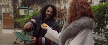 Movie still from “French Exit” (2020), directed by Azazel Jacobs – A man holding an orange in front of a woman; Medium shot, Over the shoulder angle