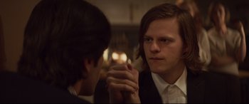 Movie still from “French Exit” (2020), directed by Azazel Jacobs – Two men sitting at a table arm wrestling; Close Up shot, Over the shoulder angle