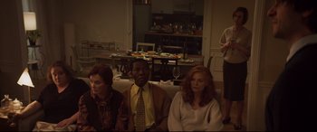 Movie still from “French Exit” (2020), directed by Azazel Jacobs – A group of people sitting on a couch in front of a table; Medium shot, High angle