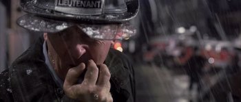 Movie still from “Frequency” (2000), directed by Gregory Hoblit – A man wearing a fireman's hat is standing in the pouring rain; Close Up shot, Low angle